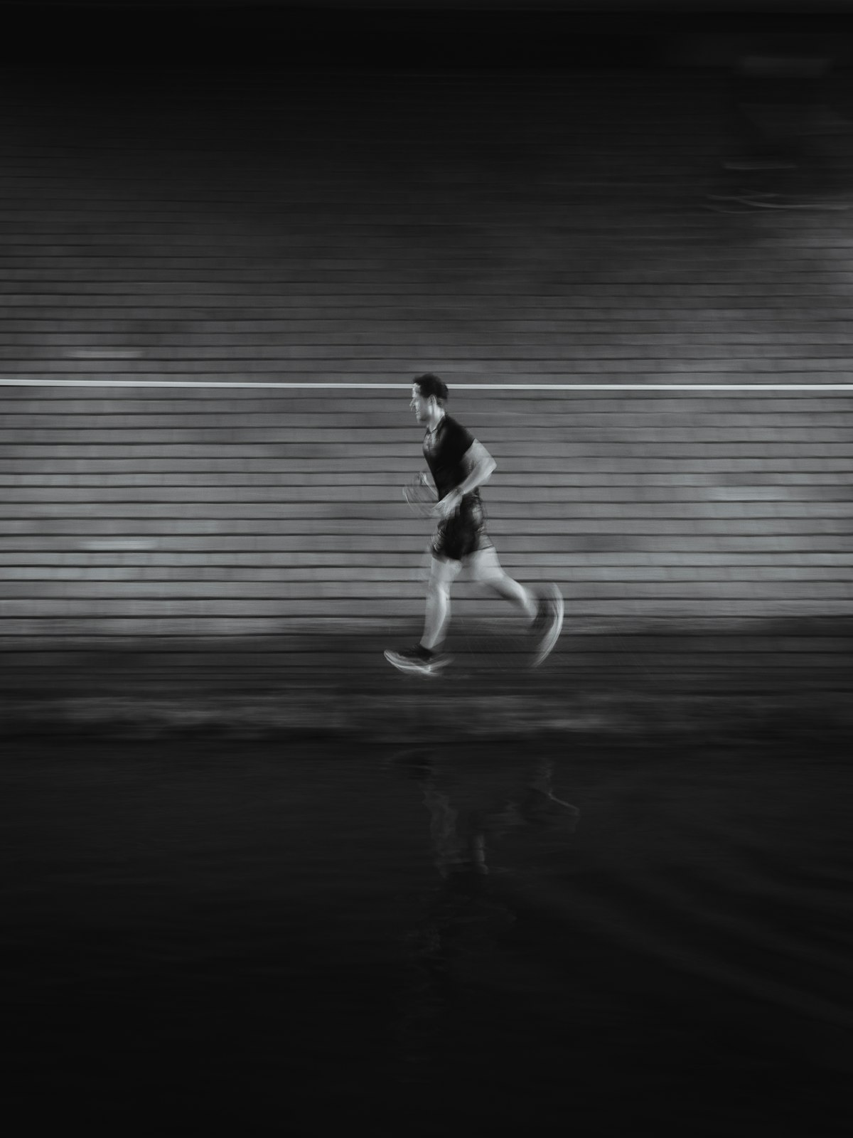 A lone runner blurred in motion against a dark wall